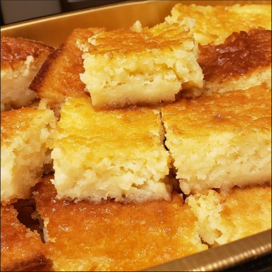 Pineapple Cake Bars displayed on a plate, garnished with shredded coconut and a scoop of vanilla ice cream.