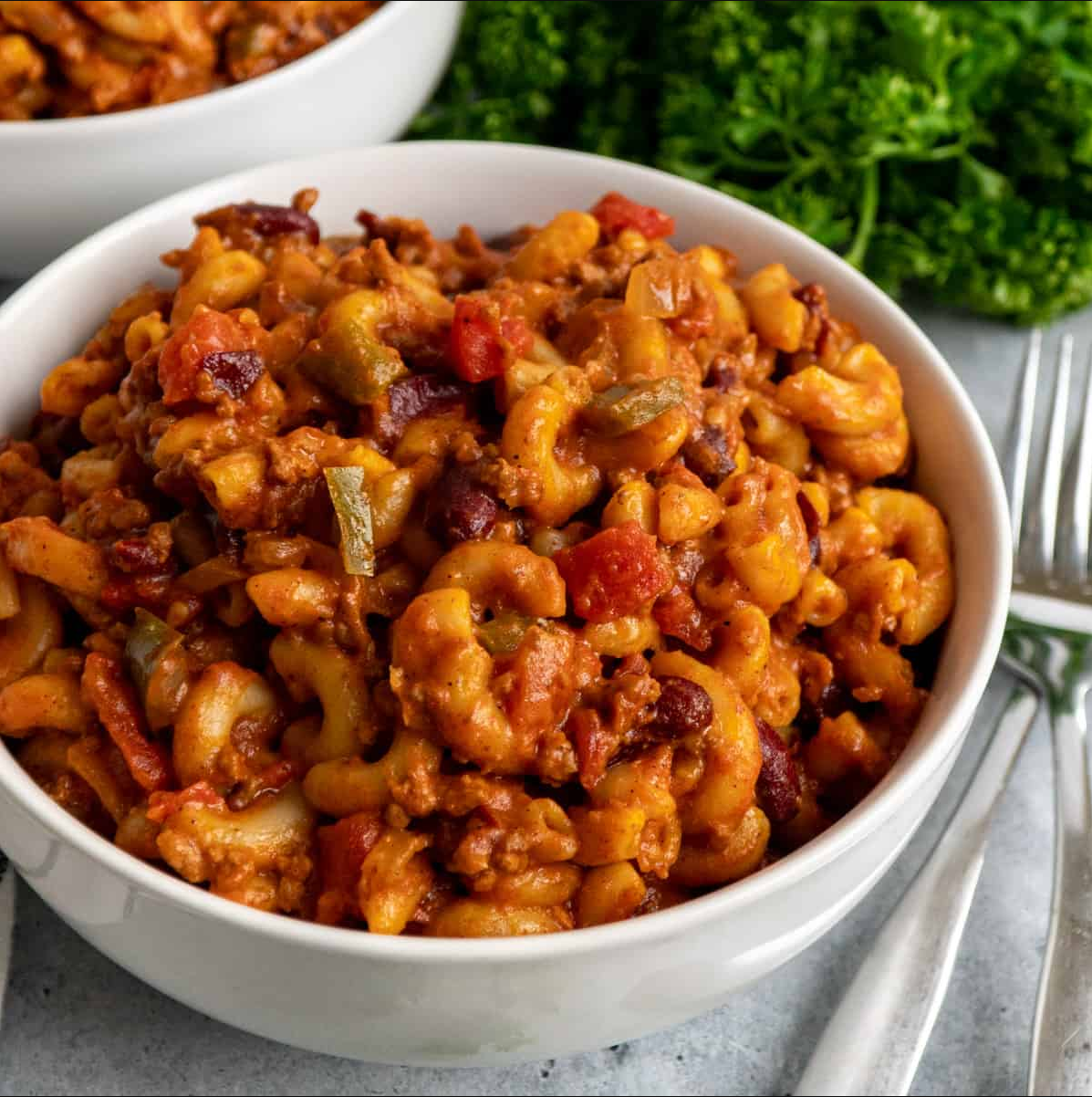 "Crockpot Cheddar Chili Mac in a slow cooker, topped with melted Cheddar cheese."