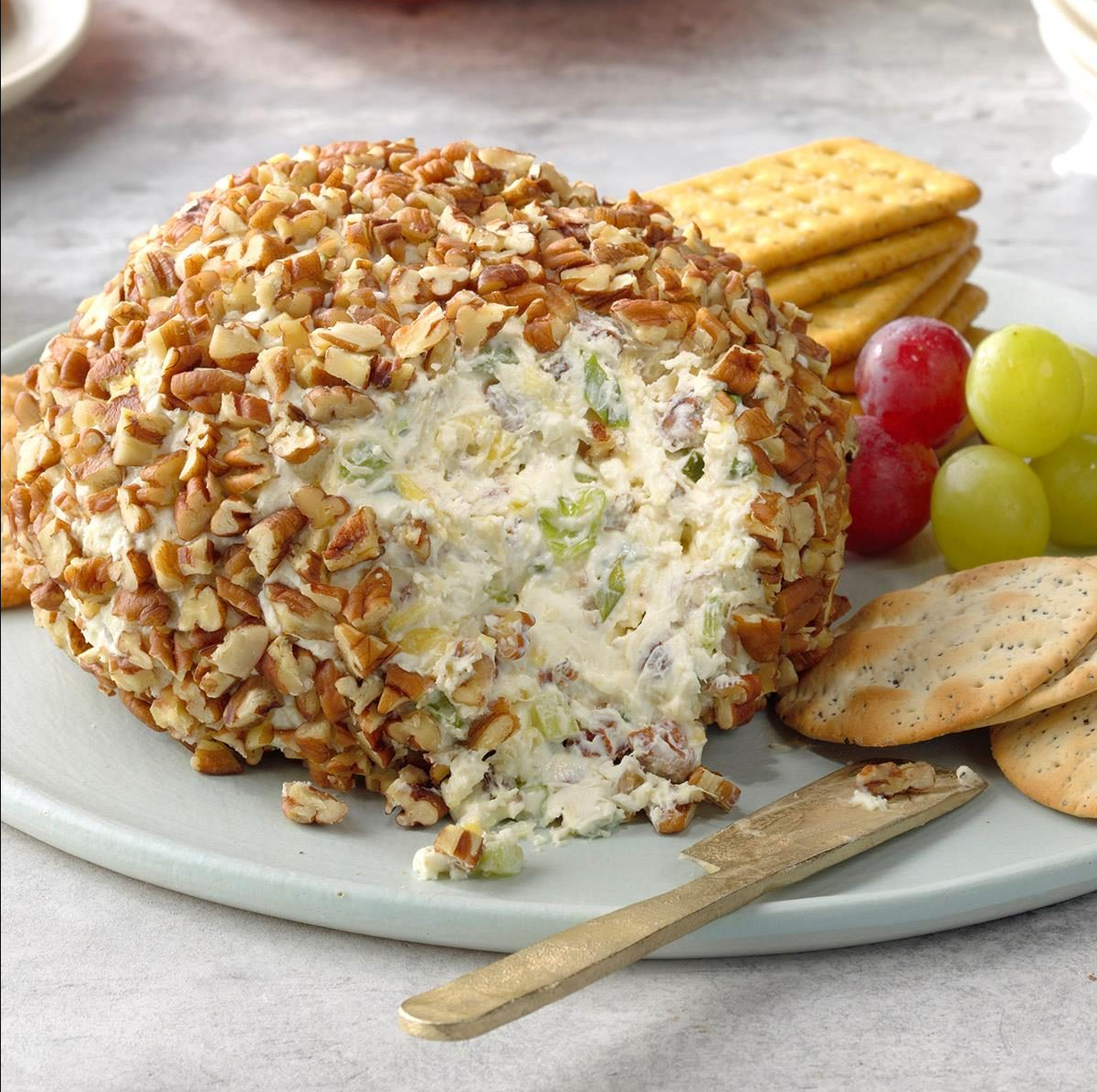 "Pineapple Pecan Cheese Ball adorned with chopped pecans, served with crackers."