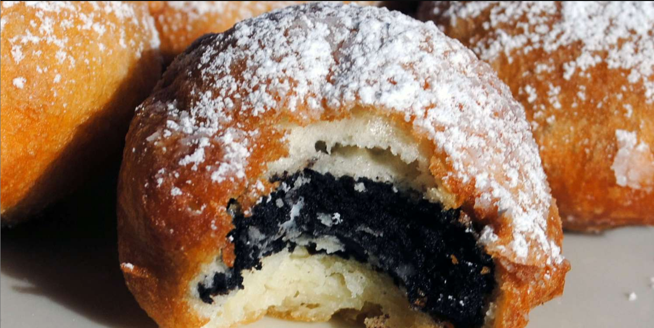 A plate of golden-brown Deep-Fried Oreos served with a dusting of powdered sugar.