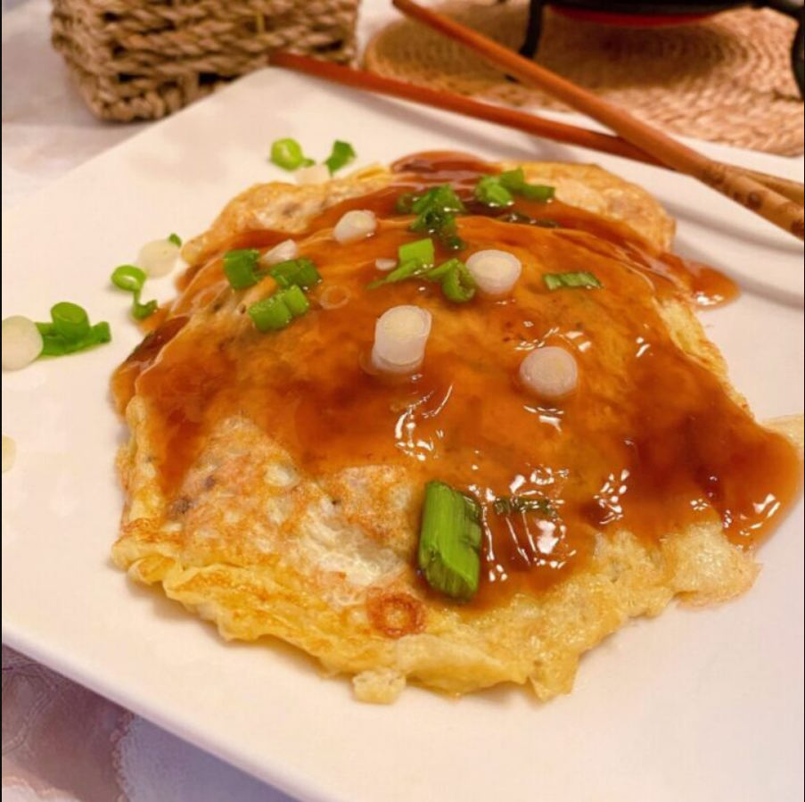 Egg Foo Young patties served on a plate, drizzled with savory gravy and garnished with green onions.