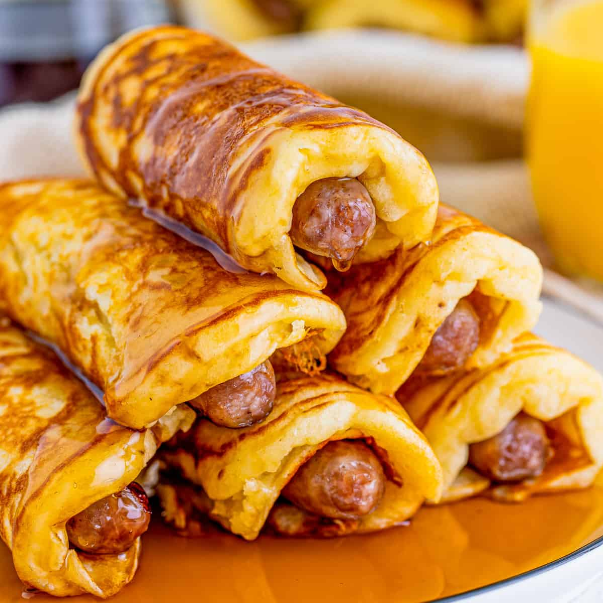 "Delicious Breakfast Pigs in a Blanket with fluffy pancakes and sausage, drizzled with syrup."