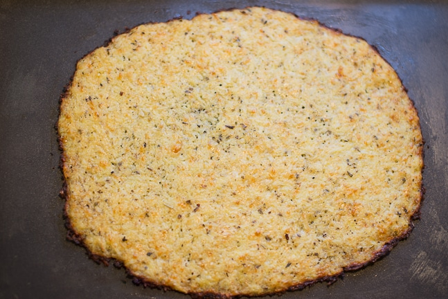 Cauliflower Pizza Crust - A golden-brown, thin crust topped with delicious, healthy ingredients.