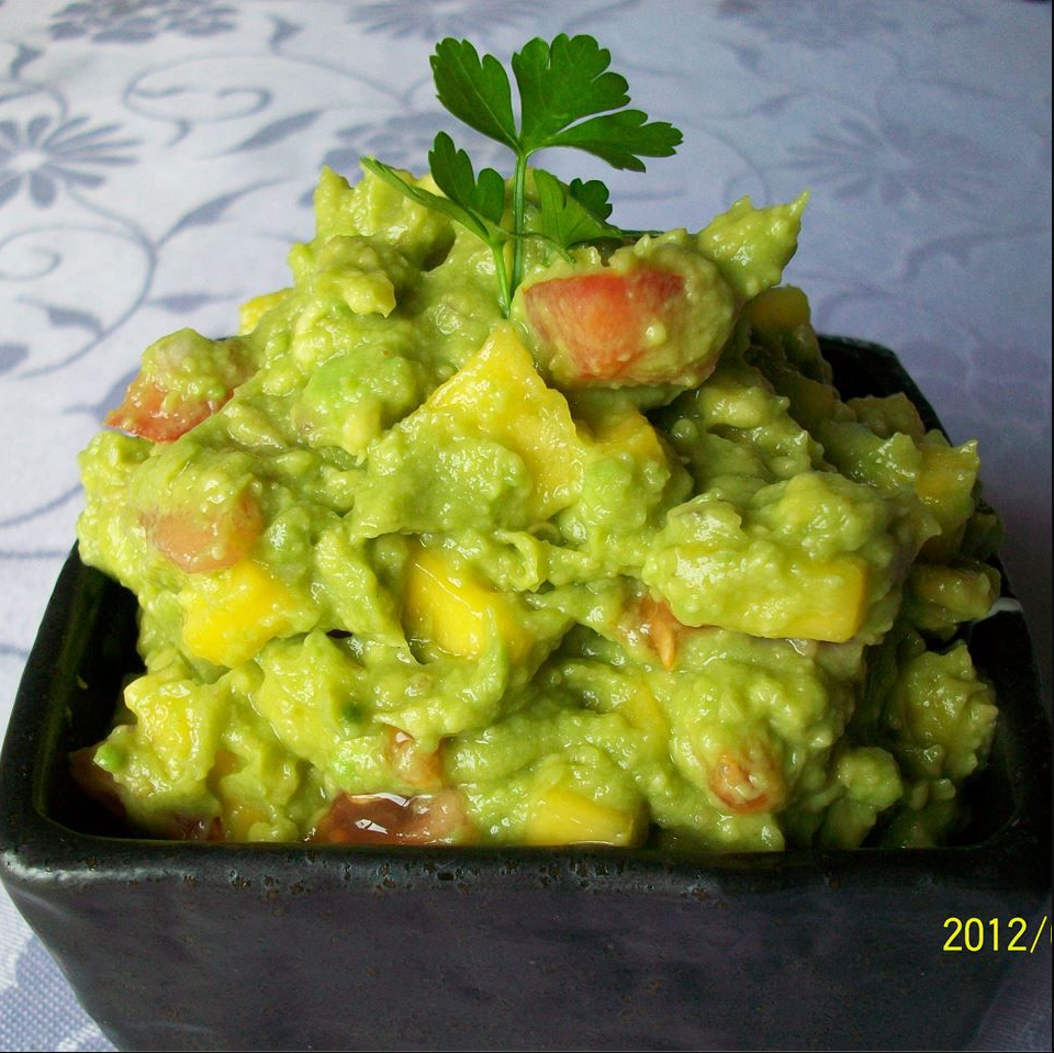 Savory Guacamole - A vibrant green bowl of mashed avocados, diced tomatoes, jalapeños, and feta cheese, served with tortilla chips.