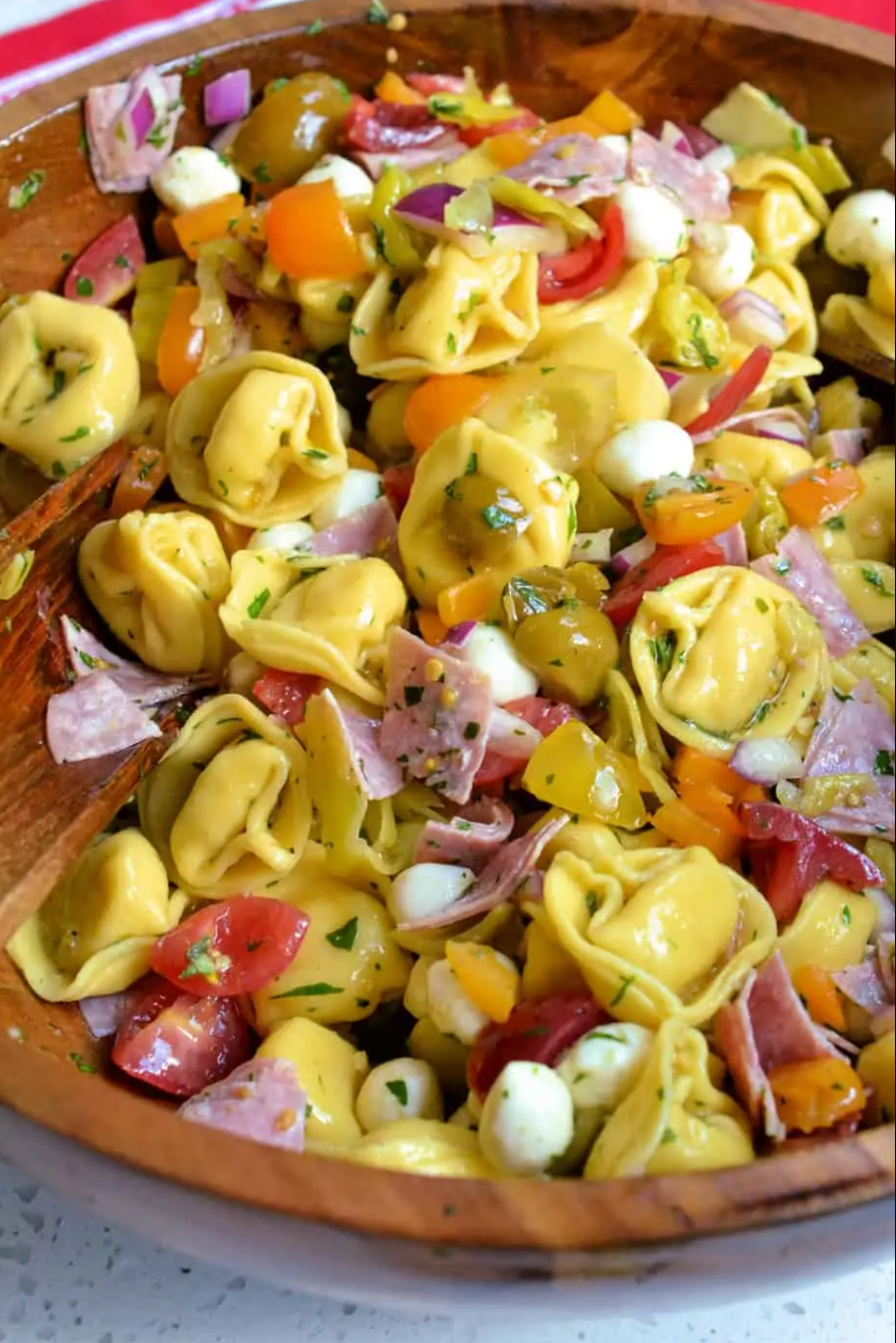 Italian Tortellini Salad - A vibrant bowl of cheese tortellini, tomatoes, peppers, mozzarella, and salami, tossed in Italian dressing.