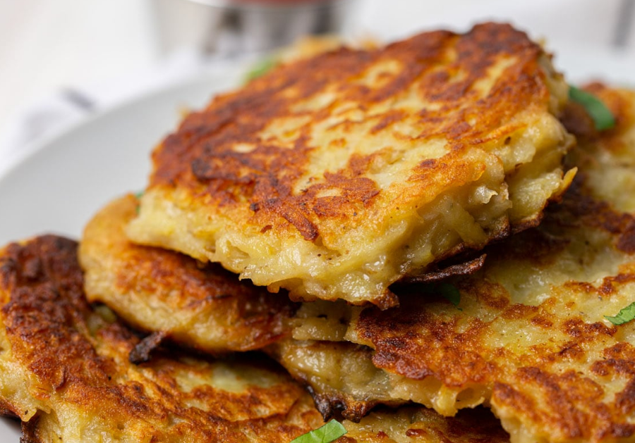 Potato Pancakes - A plate of golden-brown, crispy potato pancakes served with a dollop of sour cream. The perfect homemade delight.