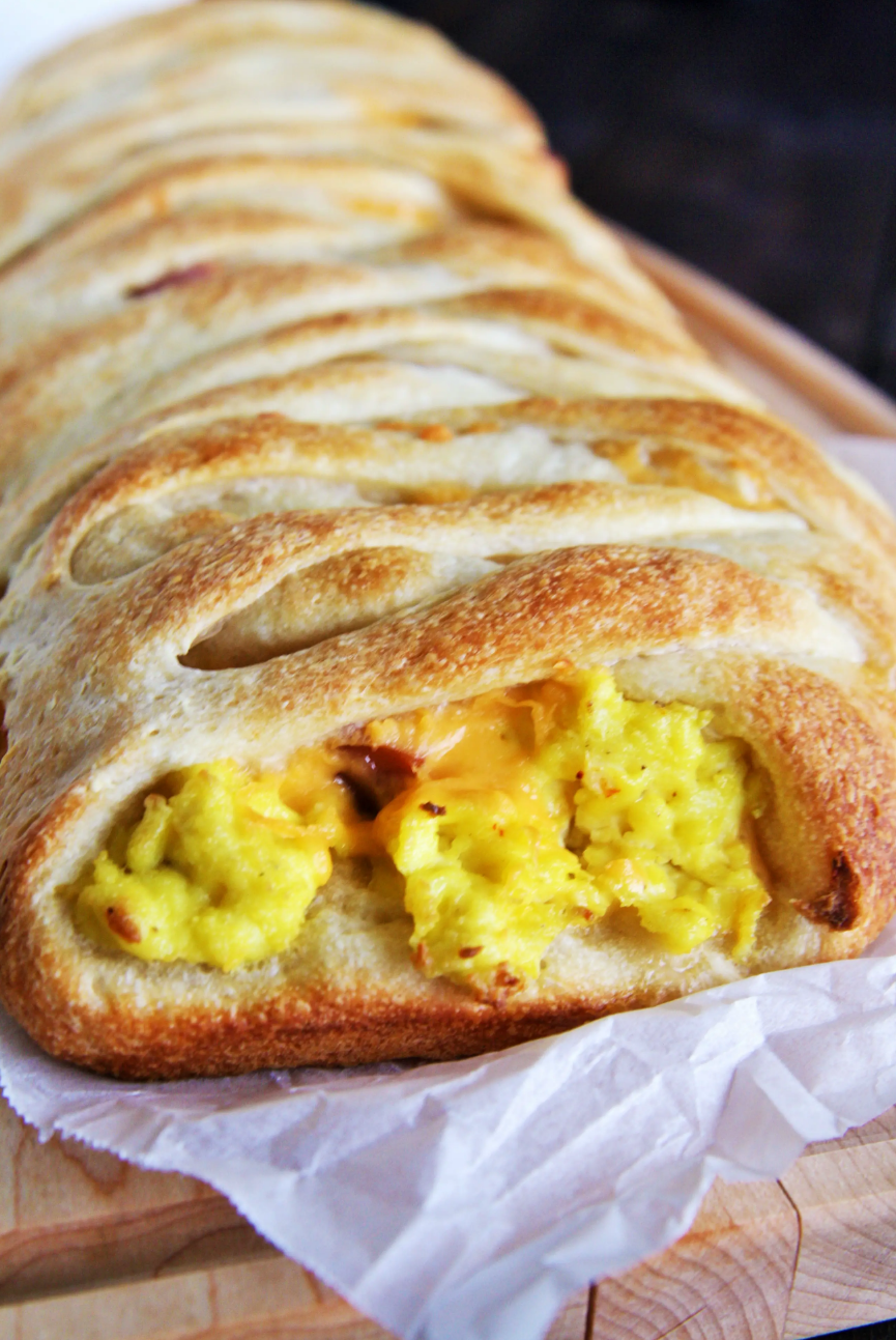 Breakfast-For-Dinner Pizza Braid - A golden-brown pizza crust with layers of sausage, scrambled eggs, bacon, and melted cheddar cheese.